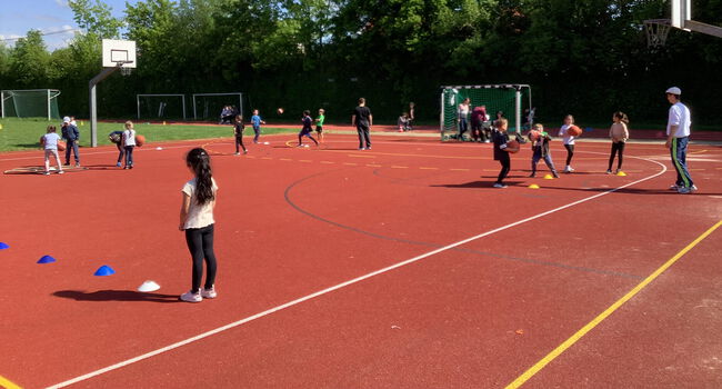 Kinder spielen verschiedene Ballsportarten auf dem Sportplatz